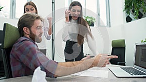 Bearded man shows interesting video to two girls in the office close up