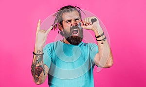 Bearded man singing in microphone with horns gesture heavy metal rock. Hipster enjoying karaoke.