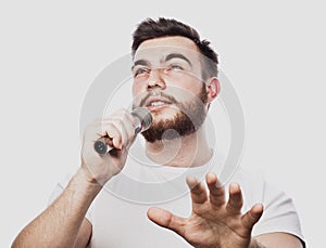 Bearded man singing to the microphone. Emotional portrait of an attractive guy with a beard on a white background