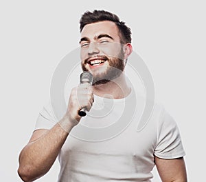 Bearded man singing to the microphone. Emotional portrait of an attractive guy with a beard on a white background