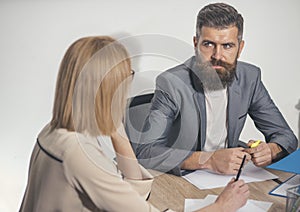 Bearded man sit at desk with woman, back view. Businessman work on business plan with businesswoman. Man with beard and