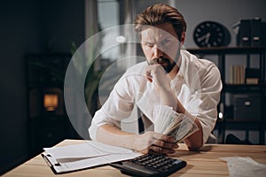 Bearded man sitting at office with dollars and documents