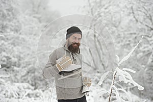 Bearded man with skates in snowy forest.