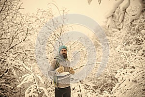 Bearded man with skates in snowy forest.