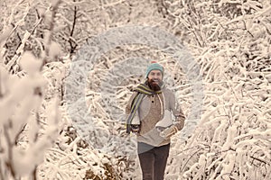 Bearded man with skates in snowy forest.