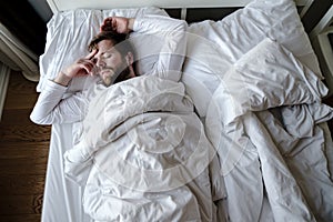 Bearded man sleeps restlessly in bed, he is alarmed and had a terrible nightmare. photo