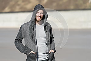 Bearded man smile in hood on sunny outdoor, fashion. Macho happy smiling in sweatshirt, casual style. Mens fashion, style, sportsw
