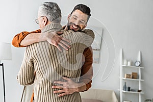 Bearded man smiling while hugging elder father at home