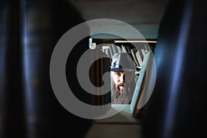 Bearded man spying through bookshelves