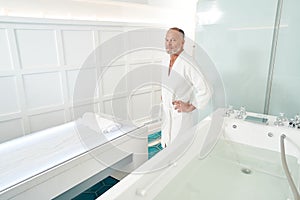 Bearded man standing by massage table in spa salon