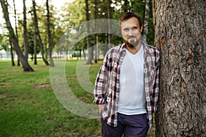 Bearded man standing near the tree in summer park