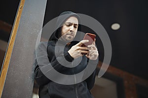 Bearded man standing next to concrete post and staring at the screen.