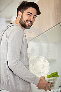 bearded man stands in kitchen holding letuce