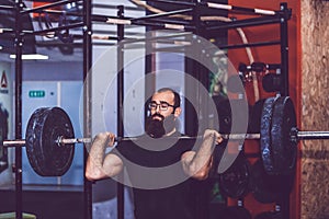 Bearded man straining to lift heavy weights during a workout session in a gym