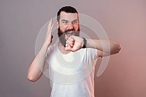 Bearded man is stressed because of the time while watching his watch.