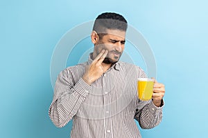 Bearded man suffering from terrible teeth pain after drinking hot or cold beverage, dental injury.