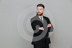 Bearded man in suit posing with crossed arms