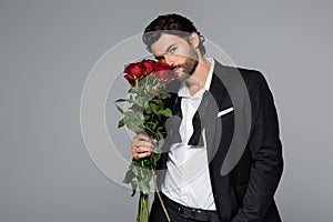 bearded man in suit smelling red