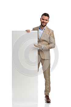 Bearded man in suit smiling and recommending empty board