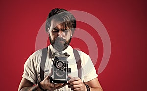 bearded man in suspenders making vintage photo. elegant businessman hold retro camera. journalist use old technology