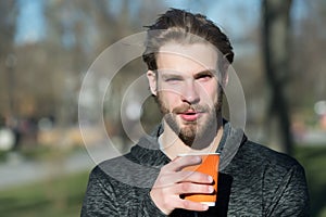 Bearded man with takeaway drink on fresh air. Macho hold disposable coffee cup in sunny park. Coffee or tea mood. Drink and food o