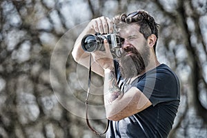 Bearded man taking photo on sunny day. Photographer concept. Man with long beard busy with shooting photos. Man with