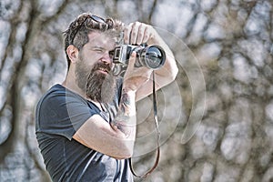 Bearded man taking photo on sunny day. Photographer concept. Man with long beard busy with shooting photos. Man with