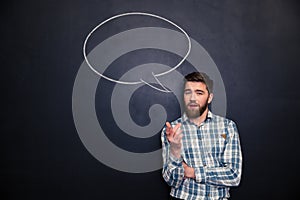 Bearded man talking over blackboard background with drawn speech bubble