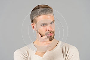 Bearded man touch beard with hand. Macho with stylish hair and healthy young skin. Guy with unshaven face and mustache. Beard groo