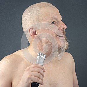 Bearded man with trimmer to adjust beard in hand. grooming and fashionable style barbershop. Beard length correction