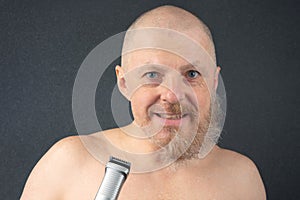 Bearded man with trimmer to adjust beard in hand. grooming and fashionable style barbershop. Beard length correction