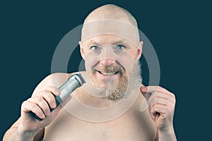 Bearded man with trimmer to adjust beard in hand. grooming and fashionable style barbershop. Beard length correction