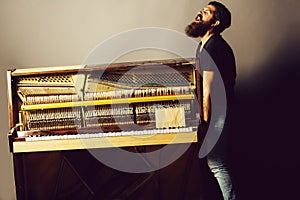 Bearded man trying to move wooden piano