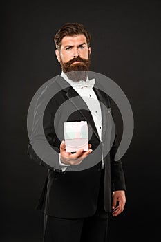 bearded man in tuxedo bow tie formalwear on black background with box. birthday
