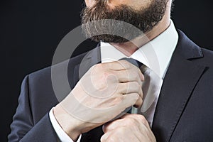 Bearded man tying up his necktie