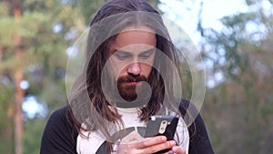 Bearded man uses mobile phone in the park