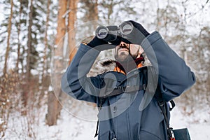 Bearded Man Using Binoculars While Winter Forest Trip photo