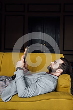 bearded man using digital tablet while lying