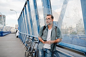 Bearded man using phone while waiting for bus.