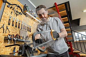 Velomechanic in professional attire servicing bicycle with specialized tools in workshop setting