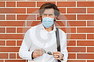 Bearded man wearing face mask outdoor. Fashionable bearded man in white shirt with bag. Coronavirus quarantine
