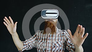 Bearded man wearing virtual reality headset and having 360 VR experience on black background