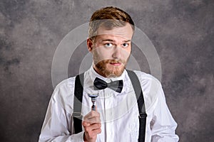 Bearded man in white shirt and bow tie showing shaver