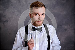 Bearded man in white shirt and bow tie showing shaver