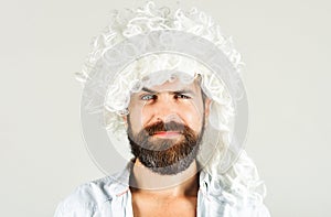 Bearded man in white wig. Smiling man with beard and mustache in curly wig. Bearded hipster in wig. Man in periwig