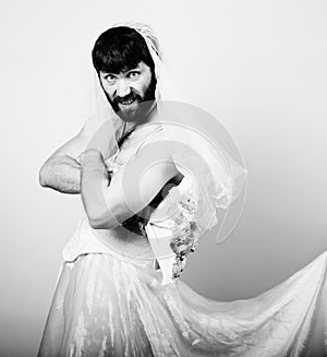 Bearded man in a woman's wedding dress on her naked body, holding a flower. funny bearded bride, black and white