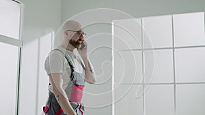 Bearded man in workwear calls on cellphone in empty office