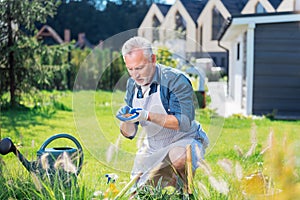 Bearded mature husband helping his family while enriching the soil in the garden