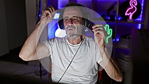 Bearded, mature man streamer in a gaming room, taking off his headset and pointing at you after a night of virtual entertainment