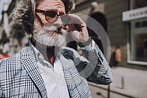 Bearded mature man touching sunglasses stock photo